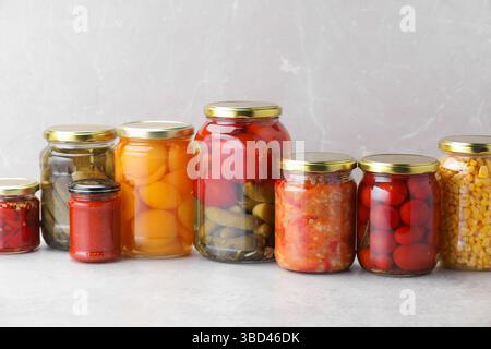 Many jars with different pickled products on light table Stock Photo