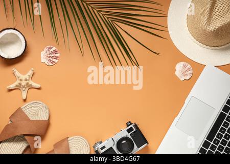 Frame made of laptop with camera, flip flops and beach decor on orange background Stock Photo