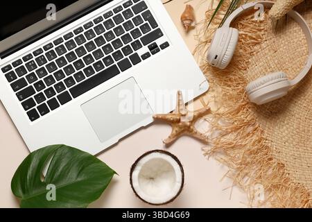 Laptop with headphones, hat and beach decor on color background Stock Photo