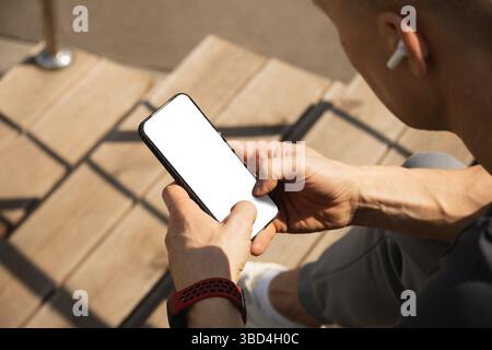 Athlete sitting on stairs and checking apps after training. Relax after training. Man listens to music. Summer season. Close up. Stock Photo