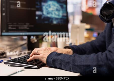 Software engineer in startup company office using computer to oversee artificial intelligence neural networks. Close up of IT professional using AI machine learning systems on PC Stock Photo