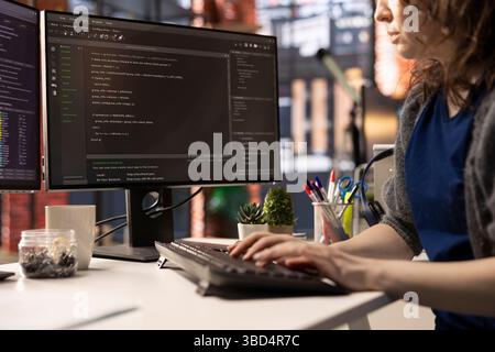 Professional software developer types code on a laptop in a sleek workspace. Expert IT freelancer doing remote work on app development, software engineering and agile coding practices. Stock Photo