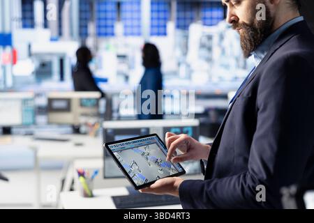Photovoltaics factory technician uses tablet to improve solar panels efficiency. Solar panels manufacturing plant worker researching cheaper and more sustainable solar solutions using device, close up Stock Photo