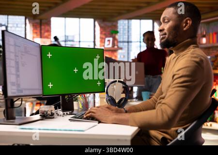 Smiling IT engineer using isolated screen PC in startup office and programming languages to build applications. Happy software development agency employee optimizing code on chroma key computer Stock Photo