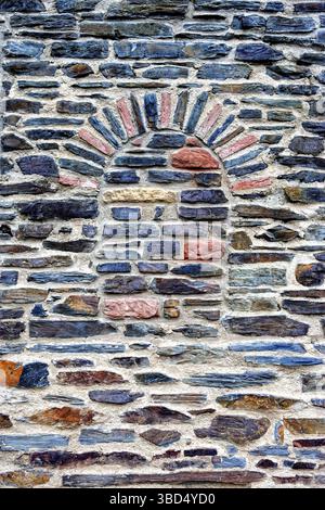 Natural stone wall with a bricked-up arch Stock Photo