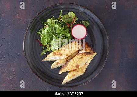 Thin pancakes stuffed with ham and melted cheese served with spinach, arugula, corn and chard salad Stock Photo