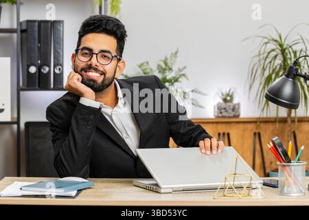 Portrait of Indian bearded businessman face freelancer at home office modern workplace working on laptop computer. Manager freelancer Arabian man work Stock Photo