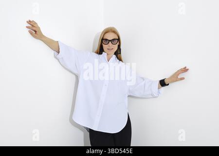 Fashion portrait of cute woman in white cotton button down shirt and black trousers on the white background Stock Photo