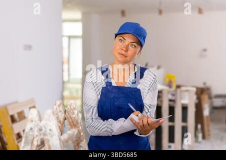 Female contractor taking notes while planning works at building site Stock Photo