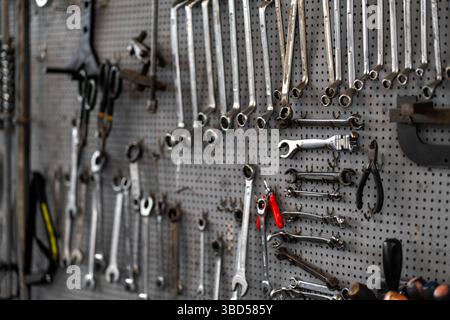 Various wrenches and hand tools hanging on pegboard in workshop. Neatly organized tools include combination wrenches, pliers, and adjustable wrenches for mechanical work Stock Photo