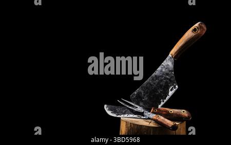 Rustic butcher meat knife, cleaver and fork on black background Stock Photo