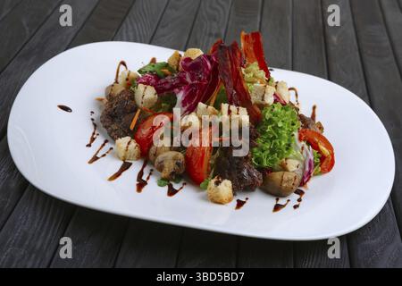 Salad with liver, bacon, grilled tomato and pepper with red cabbage and mushrooms Stock Photo