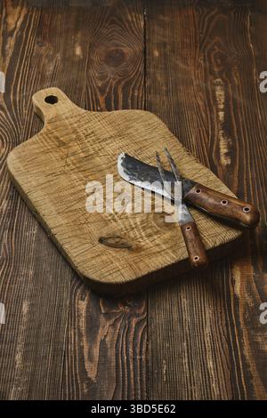 Rustic old cutting board with handmade forged knife and fork Stock Photo
