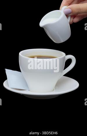 Pouring milk in coffee. Photo with clipping path isolated on black background Stock Photo