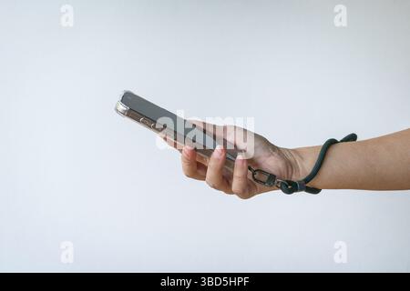 Woman holding a phone with a wrist strap. Close up view. Isolated on white background. Stock Photo