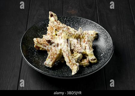 Salty bread sticks covered with melted cheese on a plate Stock Photo