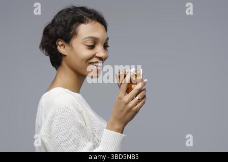 Closeup portrait of young african-american woman with a glass of cola with ice in hand Stock Photo
