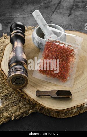 Wooden cross section with saffron in plastic package and stone mortar and mill Stock Photo