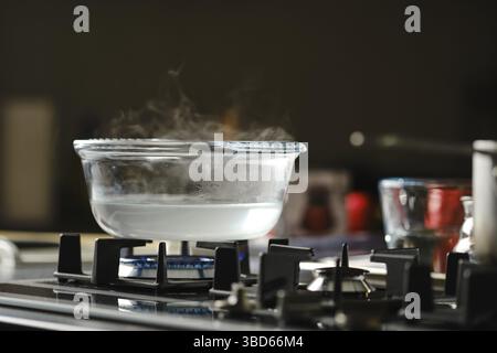 Process of boiling water in transparent casserole on gas stove Stock Photo