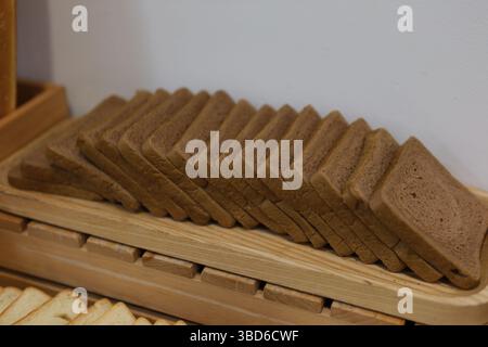 Stacked brown bread Traditional Homemade Sliced Bread on Wooden Plate Isolated. Brown Organic Cereal Bread Pieces, Round Loaf Slices on White Background Side View Stock Photo