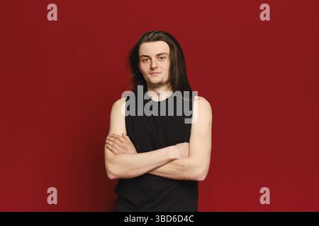 Studio portrait of young handsome man with long black hair over red background Stock Photo