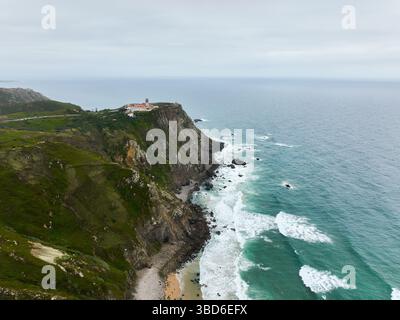 Aerial view of a lighthouse perched on a rugged rocky cliff overlooking ...