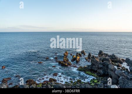 Rocky coastal landscape with ocean waves under soft evening light Stock Photo