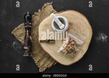 Wooden cross section with set for mulled wine spices in plastic package and stone mortar and mill Stock Photo