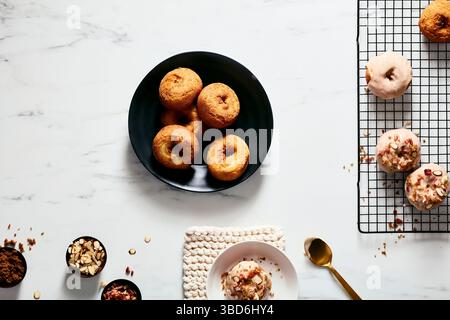 Plain and glazed donuts styled with toppings on white surface Stock Photo