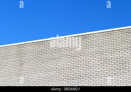 Light-colored brick wall of a building against a blue sky background textured abstract Stock Photo