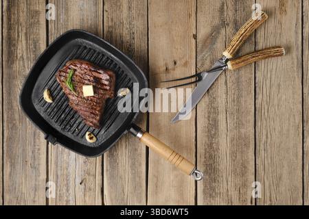 Overhead view of chuck eye steak fried on cast iron grill pan Stock Photo