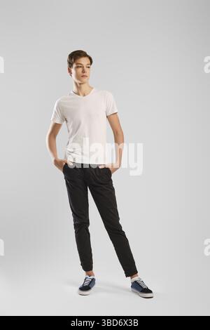 Young handsome man in black trousers and white shirt posing in studio Stock Photo