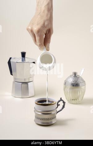 Coffee concept, pouring milk in cup of coffee, geyser coffee maker and shugar Stock Photo