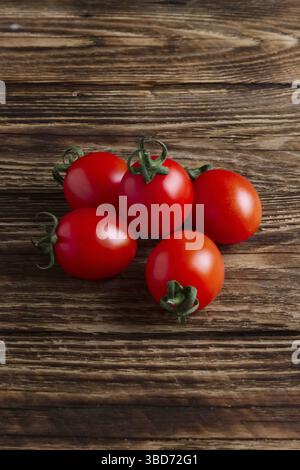 Five fresh cherry tomatoes on wooden table Stock Photo