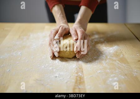 Unrecognizable woman kneads dough with her hands on the table Stock Photo