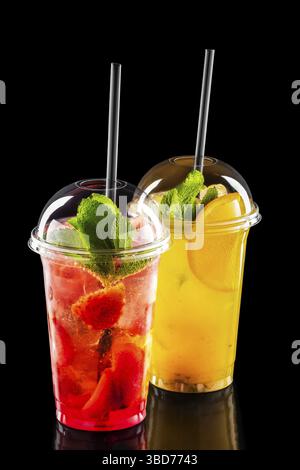 Two take away glasses with strawberry and orange lemonade isolated on black background Stock Photo