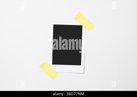 Blank polaroid photo paper stuck with sticky tape on a white background. Mockup, template, or copy space. Instant camera photo print frame Stock Photo