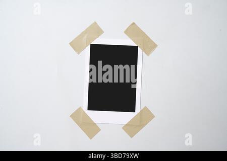 Blank polaroid photo paper stuck with sticky tape on a white background. Mockup, template, or copy space. Instant camera photo print frame Stock Photo