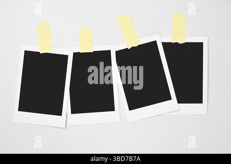 Four blank polaroid photo papers stuck with sticky tape on a white background. Mockup, template, or copy space. Instant camera photo print frame Stock Photo