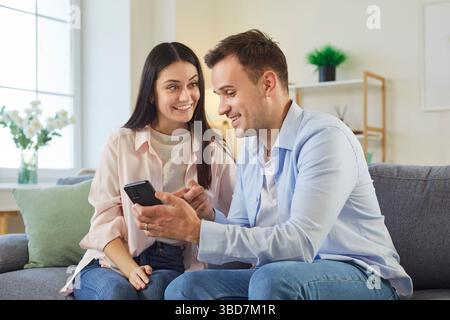 Happy Married Couple Using Phone For Online Leisure Stock Photo