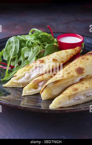 Thin pancakes stuffed with ham and melted cheese served with spinach, arugula, corn and chard salad Stock Photo