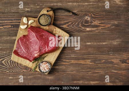 Overhead view of raw top side beef steak on wooden tabletop with place for text Stock Photo