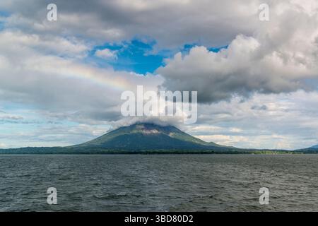 View from Lake Nicaragua on volcano Concepcion with rainbow and heavy clouds around its top. Nicaragua. Stock Photo