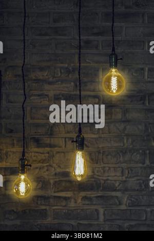 Vintage edison light bulbs on wire with brick wall on background Stock Photo