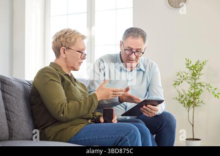 Focused Senior Couple Using Tablet Pc At Home For Online Activities Stock Photo