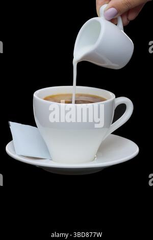Pouring milk in coffee. Photo with clipping path isolated on black background Stock Photo
