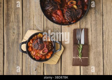 Overhead view of cast iron skillet with ossobuco on wooden table Stock Photo