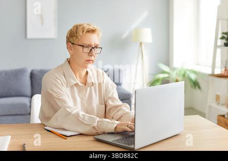 Thoughtful focused senior mature businesswoman working at laptop in office, busy using online app Stock Photo