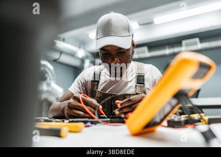Electrician working diligently on a circuit board in a modern workshop during the daytime with various tools around Stock Photo
