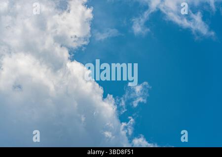 Fluffy white clouds in a bright blue daytime sky Stock Photo